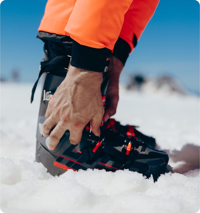 Skieur ajustant ses chaussures de ski dans la neige, prêt à partir