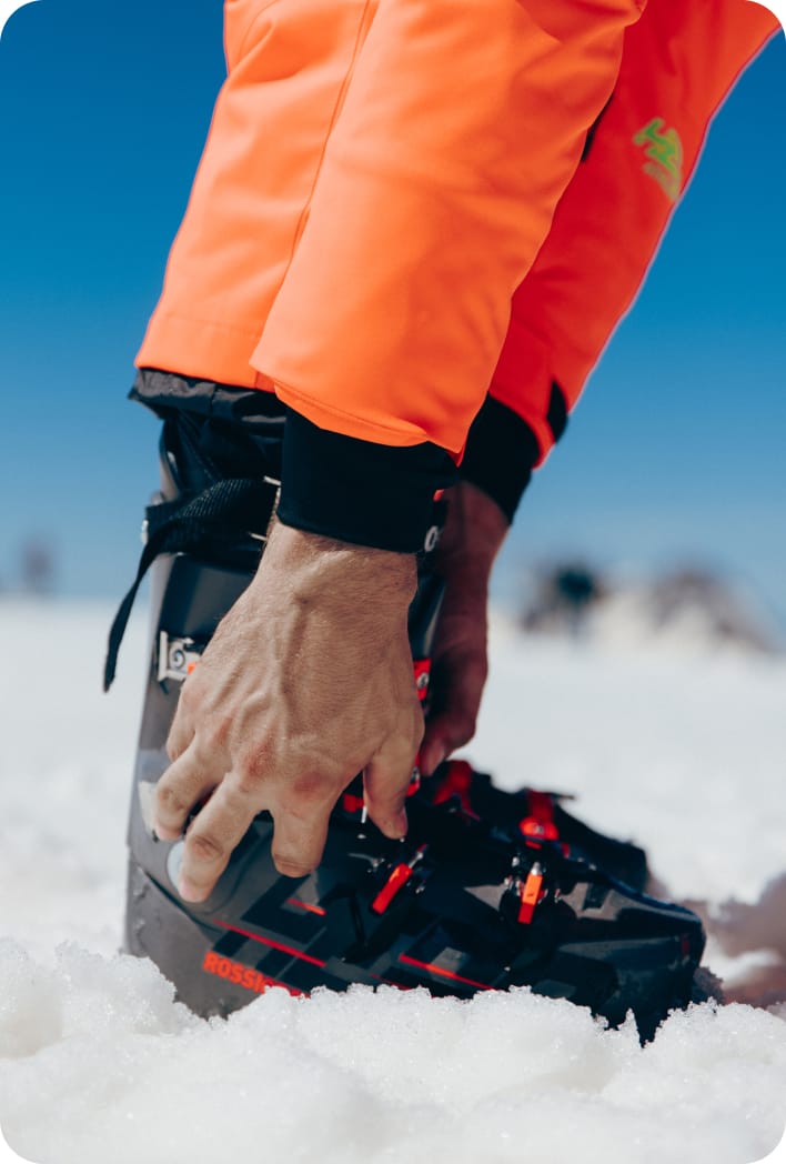 Skieur ajustant ses chaussures de ski dans la neige, prêt à partir