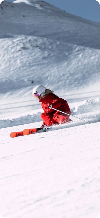 Eine Skifahrerin auf der Piste in einem roten Rossignol-Outfit.