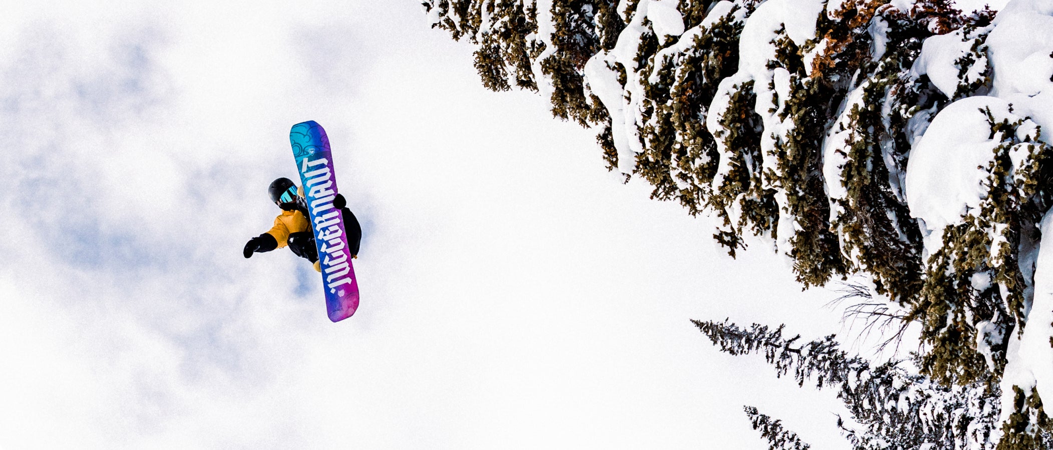 Snowboarder captured from below mid-air jump, showcasing the base of a Rossignol snowboard