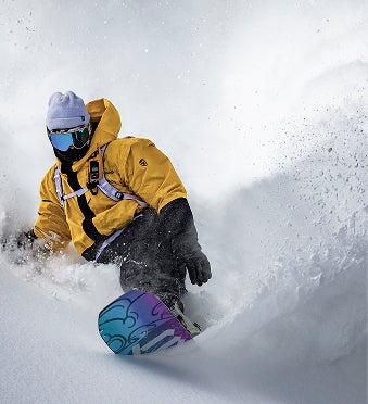 Relaxed snowboarder riding downhill through fresh powder snow in the mountains