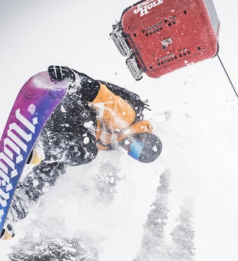 Snowboarder performing a freestyle trick while grabbing the board and spraying snow in mid-air