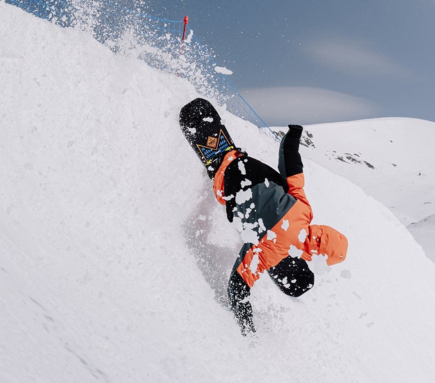 Snowboarder performing a freestyle trick with one hand on the snow and the Rossignol snowboard lifted in the air