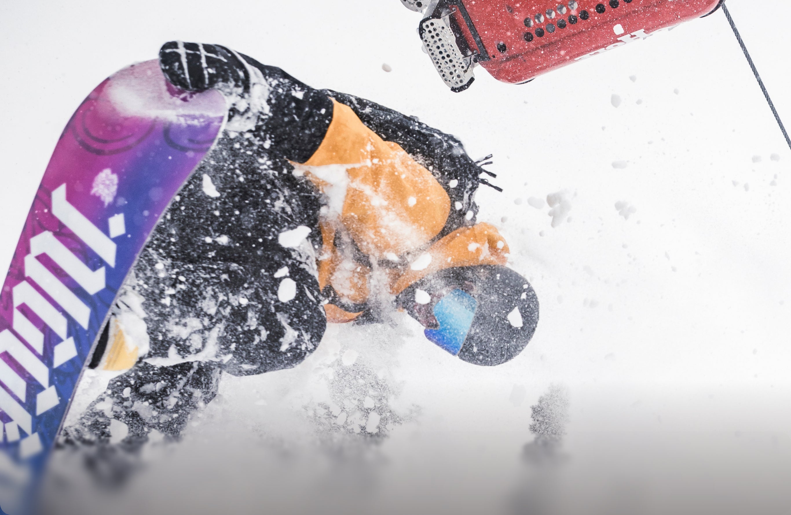 Snowboarder performing a freestyle trick while grabbing the board and spraying snow in mid-air