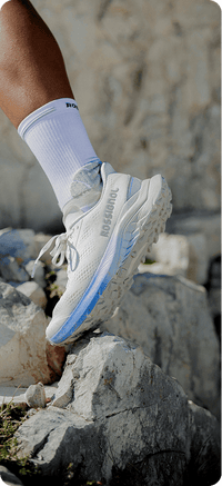 Zoom auf einen Rossignol Venosk Trailschuh beim Tragen. Die Läuferin läuft über große Felsen.