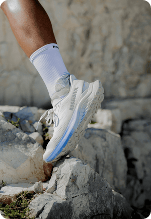 Zoom auf einen Rossignol Venosk Trailschuh beim Tragen. Die Läuferin läuft über große Felsen.