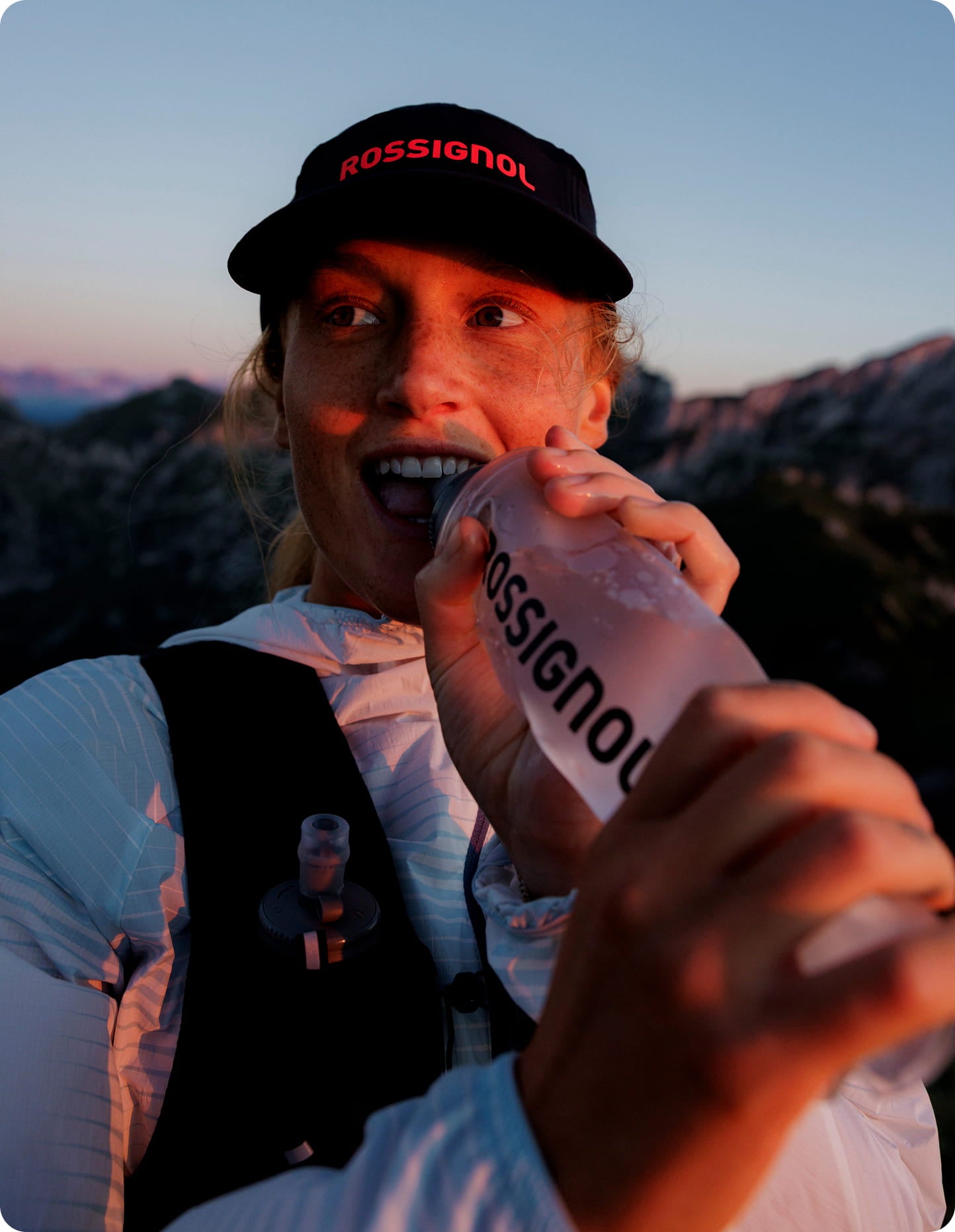 Atleta all’aperto che tiene una borraccia morbida Rossignol durante il trail running, con paesaggio montano.