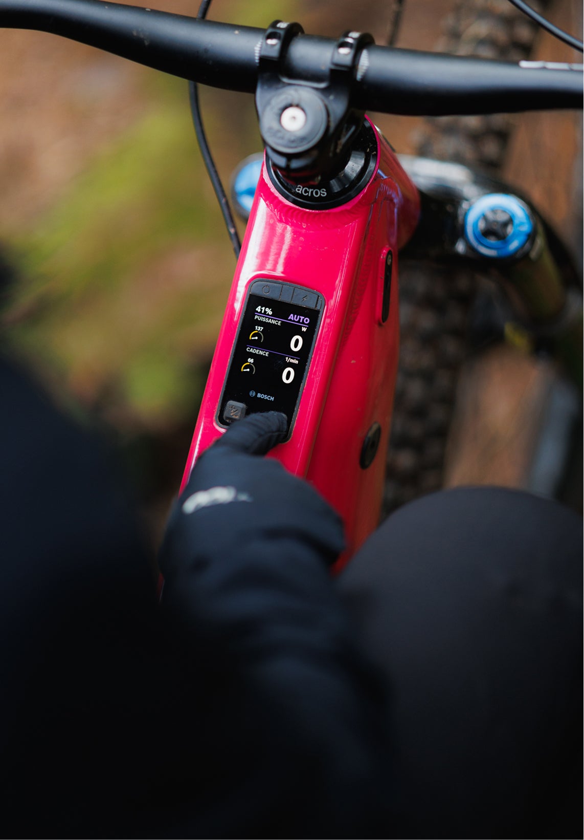 Close-up of the integrated control display on the frame of the Rossignol After Hours electric mountain bike, showing riding information, with red frame and handlebars visible.