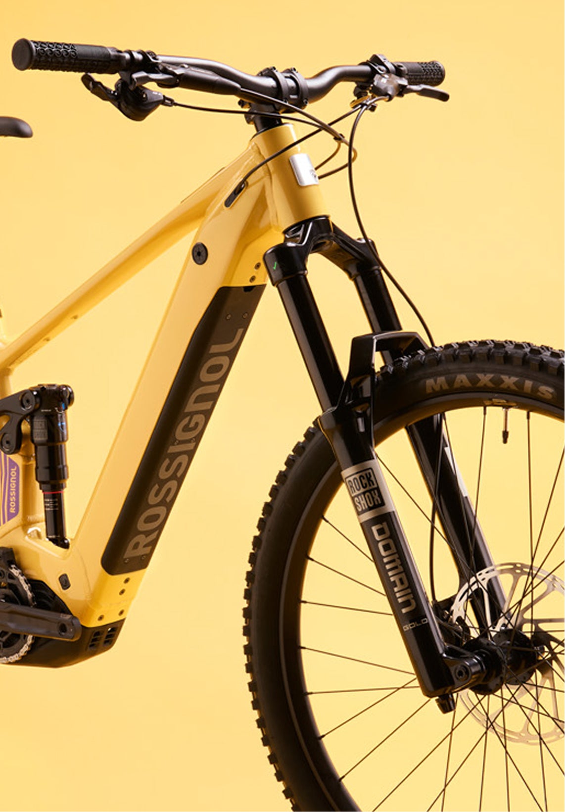 Close-up of the front section of the Rossignol After Hours Deore 12, showing the yellow frame, black suspension fork, front wheel, handlebars, and Rossignol logo on the down tube.
