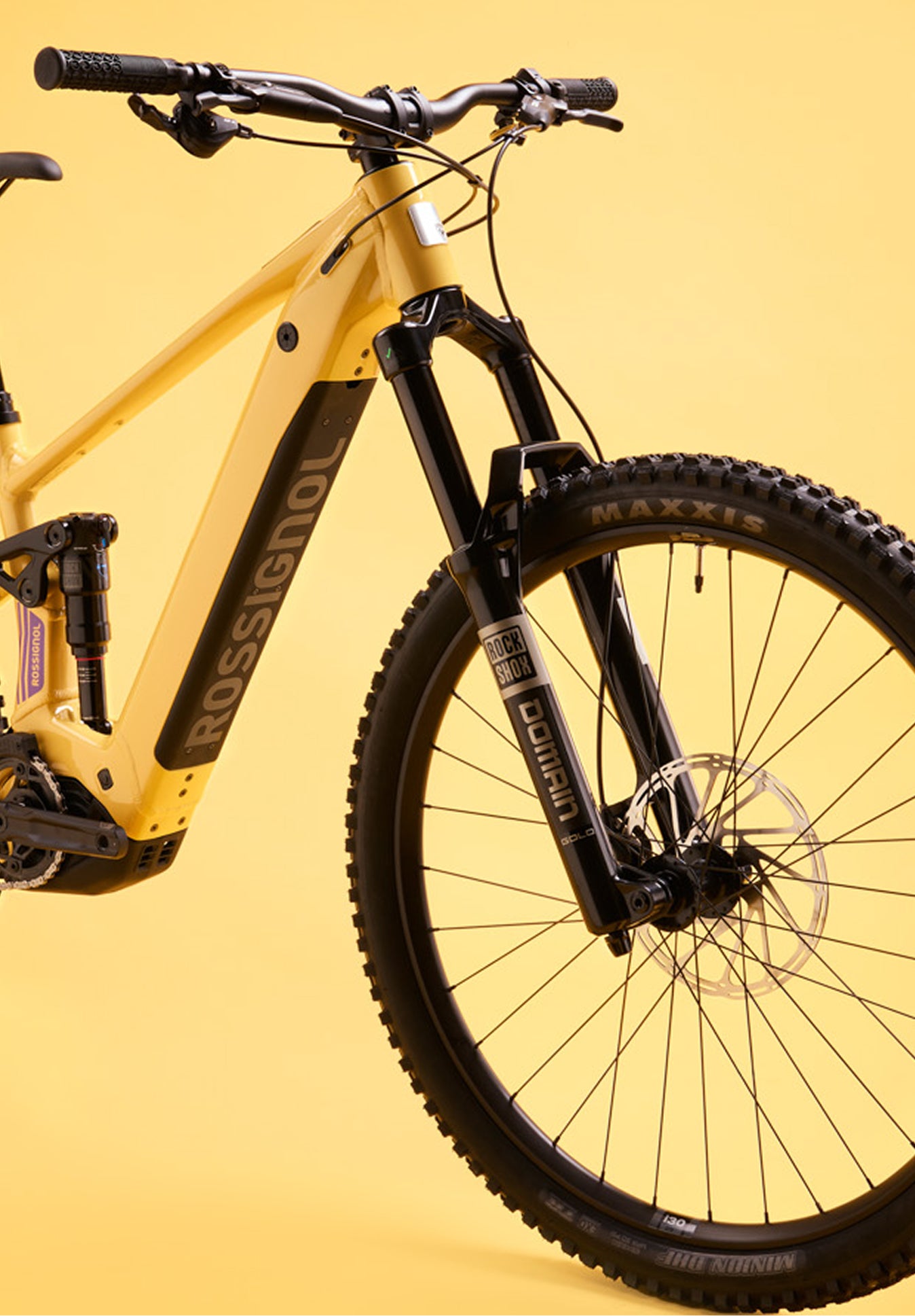 Close-up of the front section of the Rossignol After Hours Deore 12, showing the yellow frame, black suspension fork, front wheel, handlebars, and Rossignol logo on the down tube.