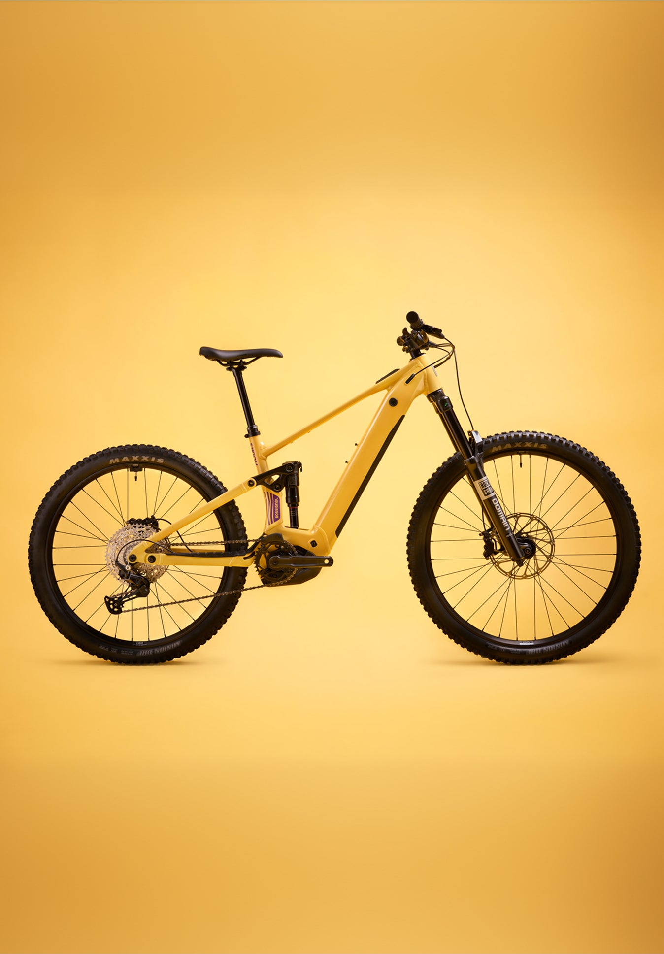 Yellow Rossignol After Hours Deore 12 electric mountain bike shown in side view, featuring full suspension, wide tires, and a sturdy frame on a plain yellow background.