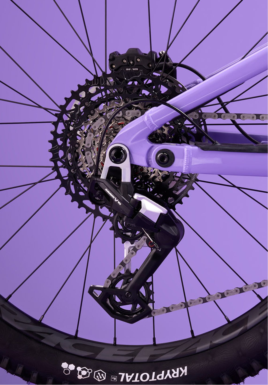 Close-up of the rear drivetrain of the Rossignol After Hours Eagle 90, showing cassette, derailleur, and chain on a spoked wheel with a purple frame.