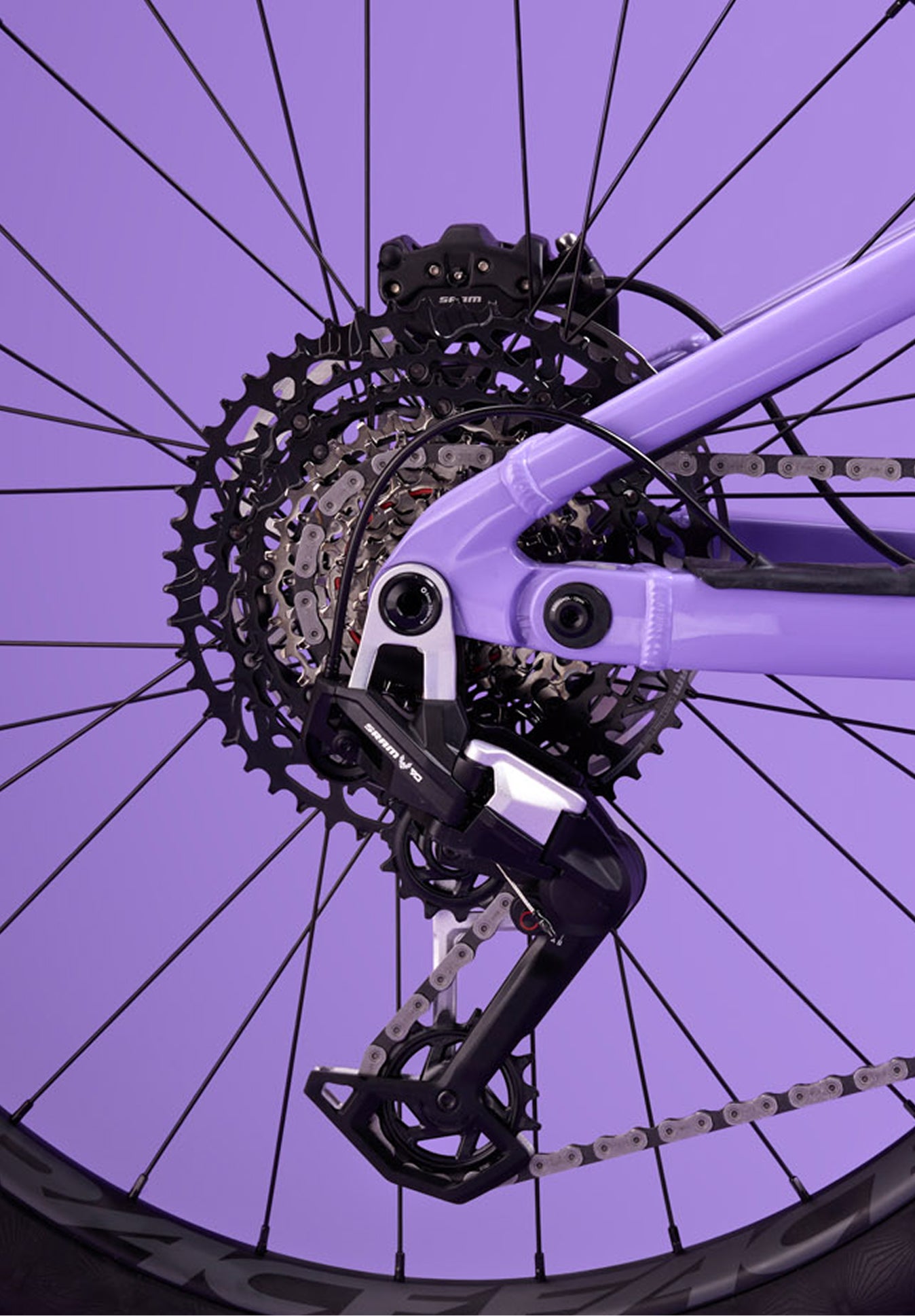 Close-up of the rear drivetrain of the Rossignol After Hours Eagle 90, showing cassette, derailleur, and chain on a spoked wheel with a purple frame.