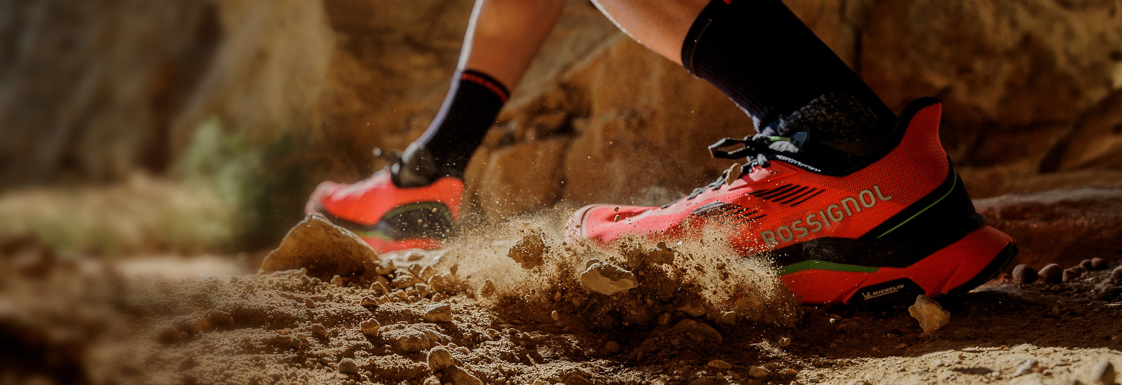 Chaussure de trail Rossignol Vezor en action sur un terrain rocheux et poussiéreux, mettant en avant son accroche, sa stabilité et sa propulsion sur les sentiers techniques.