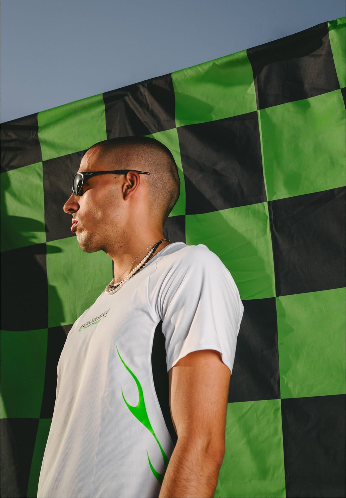 Homme portant le SAPA ULTRA TEE de Rossignol en contre-plongée sur un fond à damier noir et vert