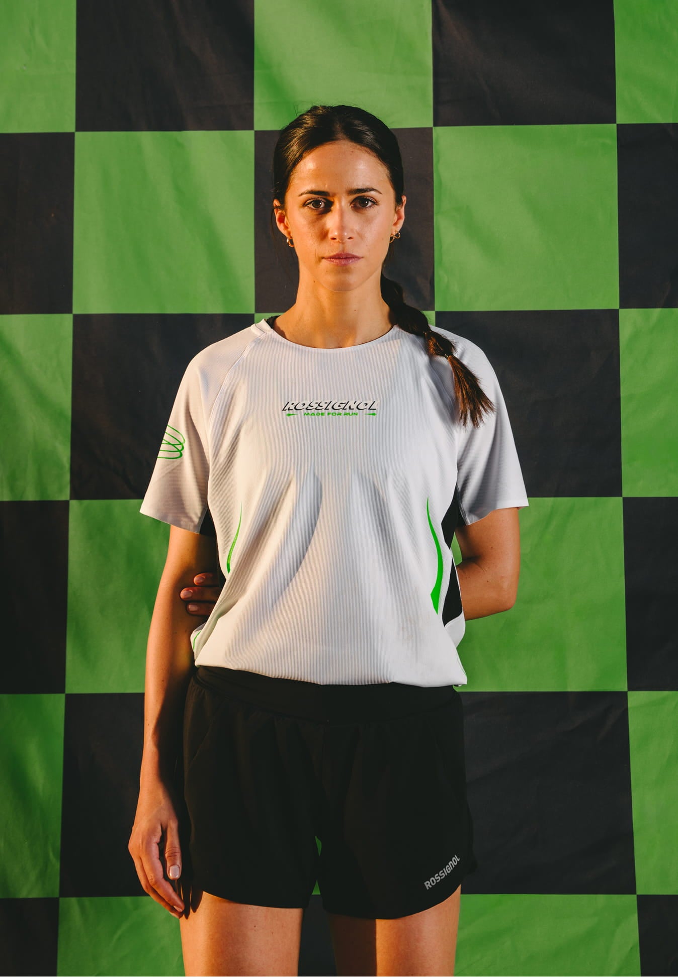 Female athlete wearing the Rossignol SAPA ULTRA TEE WOMAN SP against a black and green checkerboard background