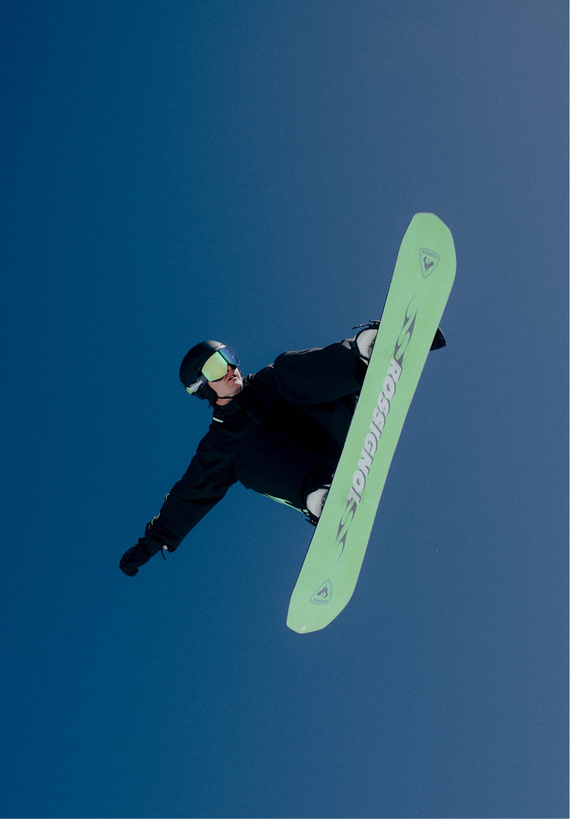 Snowboarder en plein saut avec le snowboard relevé dans les airs
