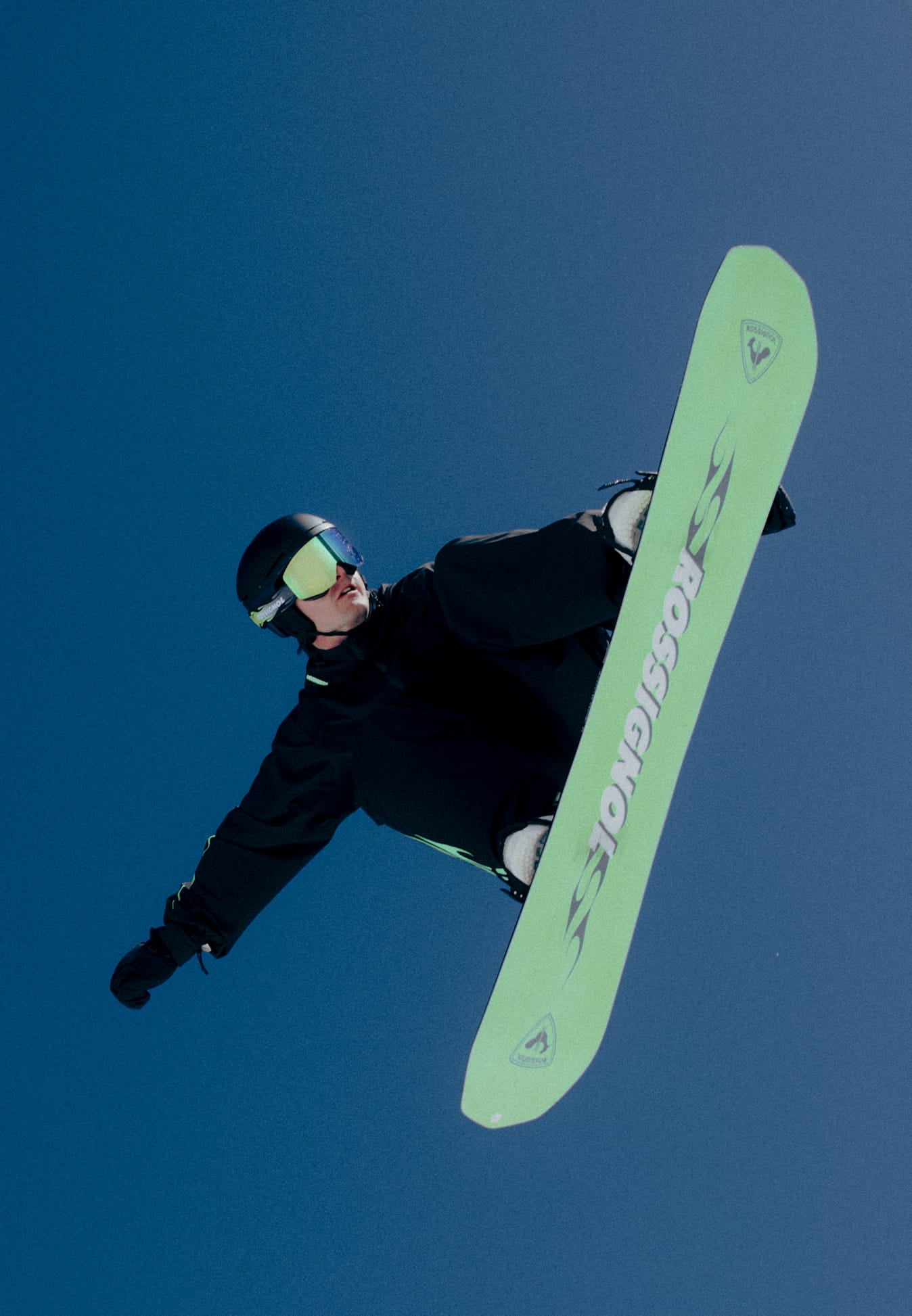 Snowboarder en plein saut avec le snowboard relevé dans les airs