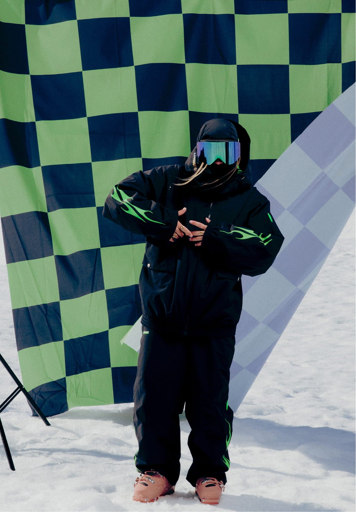Female athlete wearing the Rossignol ALLTRACK 2L SHELL JACKET in front of a green and black checkerboard flag
