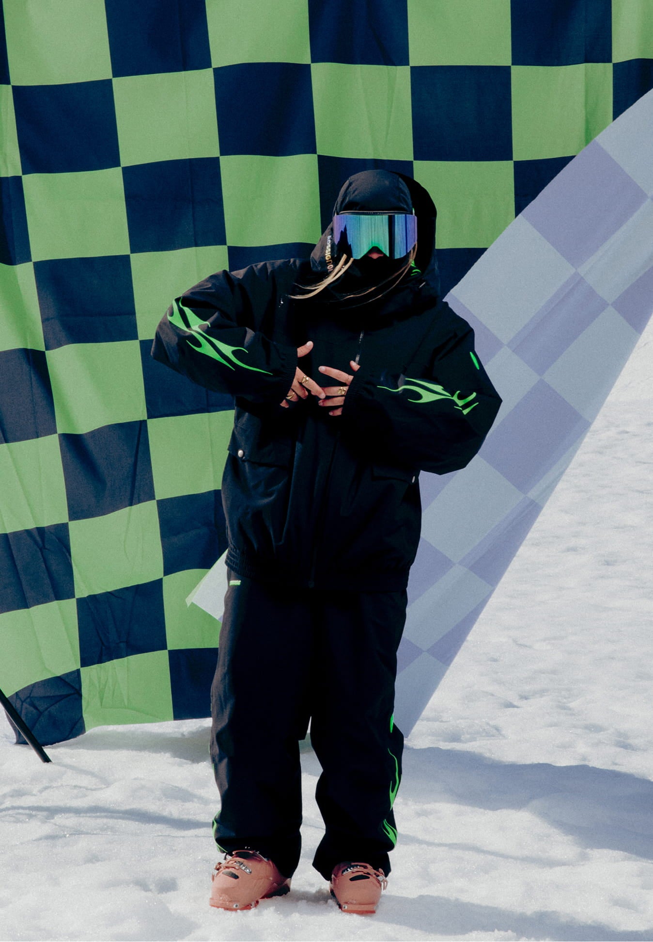 Female athlete wearing the Rossignol ALLTRACK 2L SHELL JACKET in front of a green and black checkerboard flag