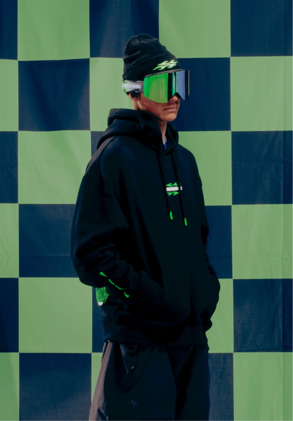 Athlete wearing the Rossignol SUPER PROJECT HOODIE in front of a green and black checkerboard background