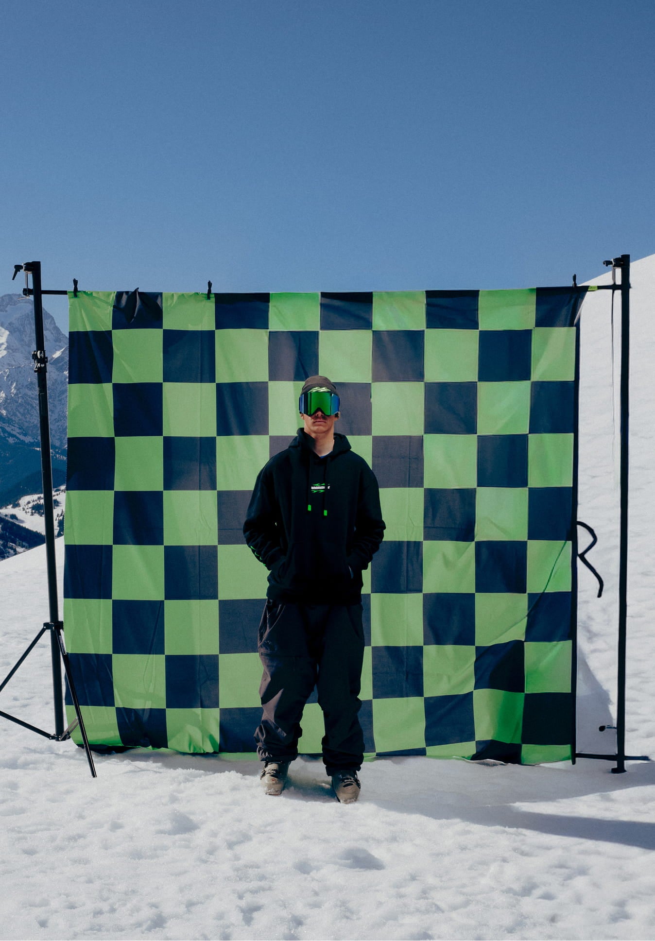 Snowboarder standing facing the camera wearing the Rossignol SUPER PROJECT HOODIE in a mountain landscape