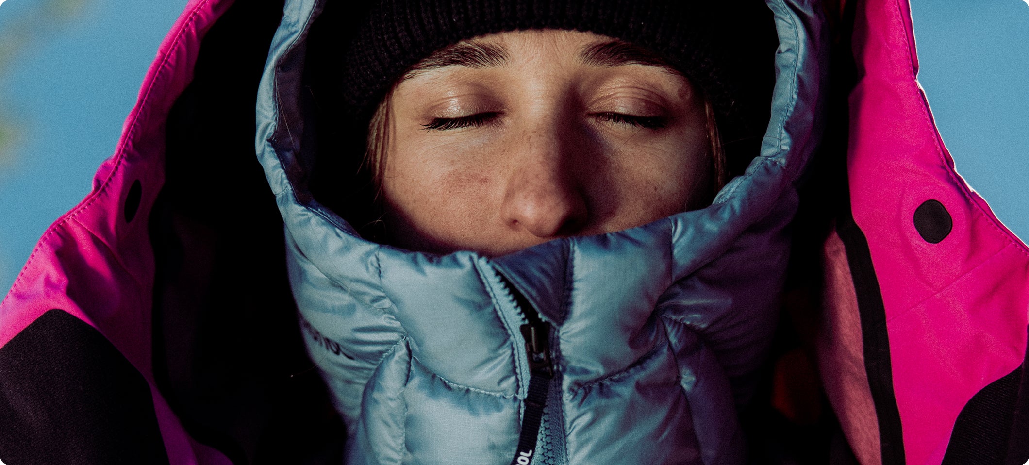 Nahaufnahme einer Person mit einer isolierten Rossignol Jacke und Mütze, deren hochgeschlossener Kragen Schutz vor kalten Witterungsbedingungen bietet.