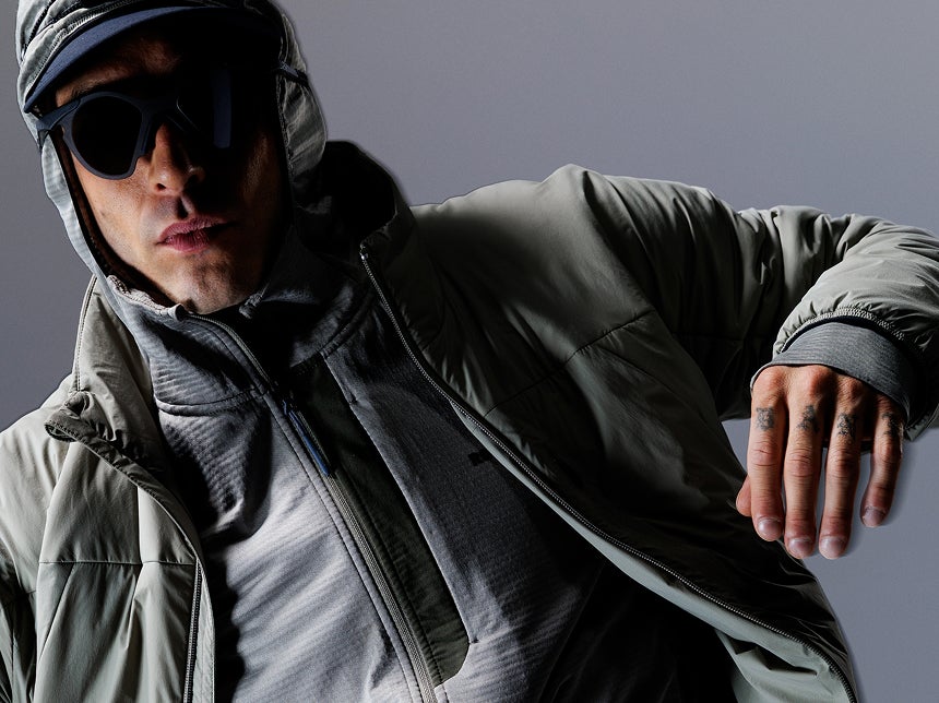 Nahaufnahme einer Person mit technischer Rossignol Jacke und Handschuhen vor einem Studiohintergrund.