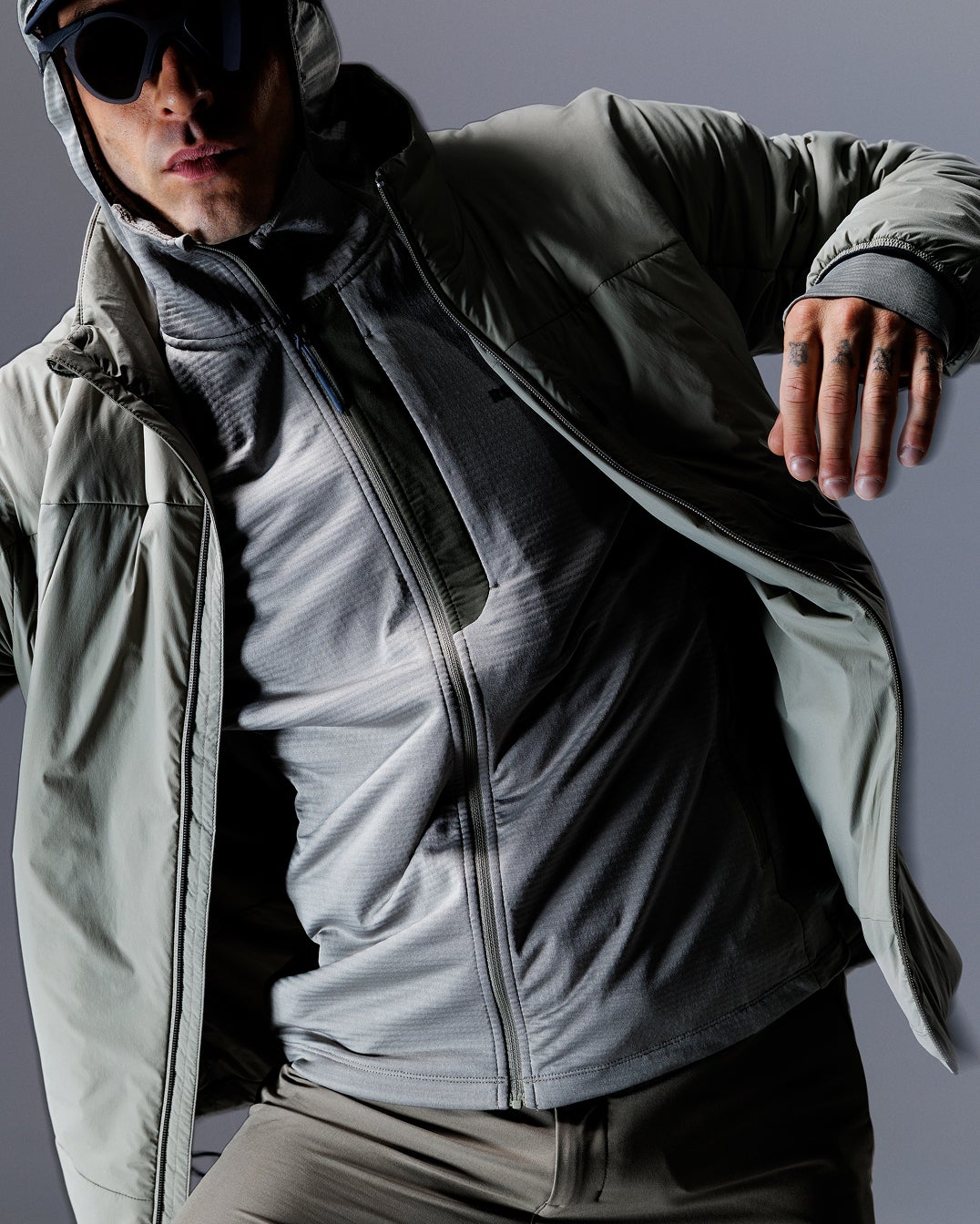 Nahaufnahme einer Person mit technischer Rossignol Jacke und Handschuhen vor einem Studiohintergrund.