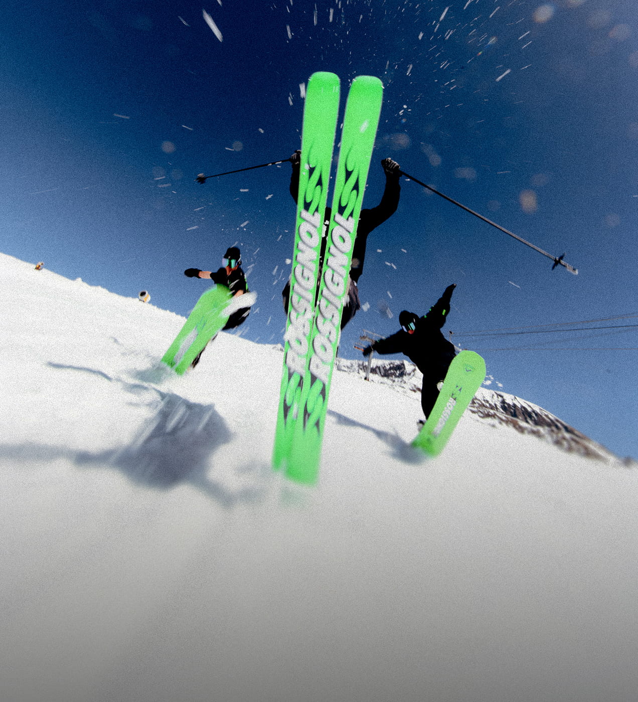 3 freeride riders using Super Blackops and Super Revenant skis from Rossignol's 2026 Super Project collection. They are performing jumps showing the bright neon green topsheet of their equipment.