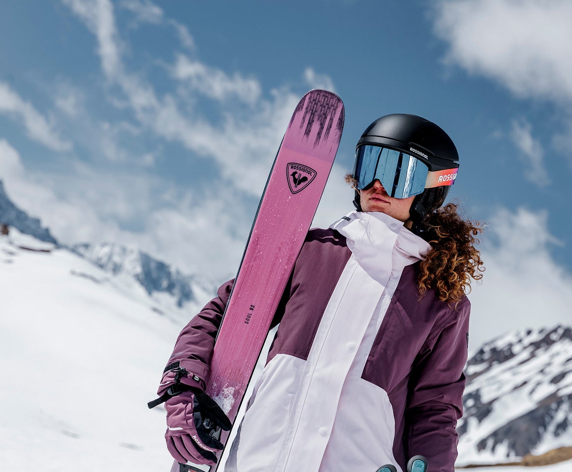Rossignol freeride skier carrying pink skis in the mountains
