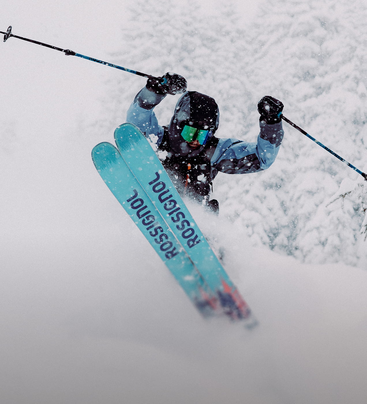 A freeride skier in deep powder, performing a jump with the tips of his Rossignol Sender skis visible.