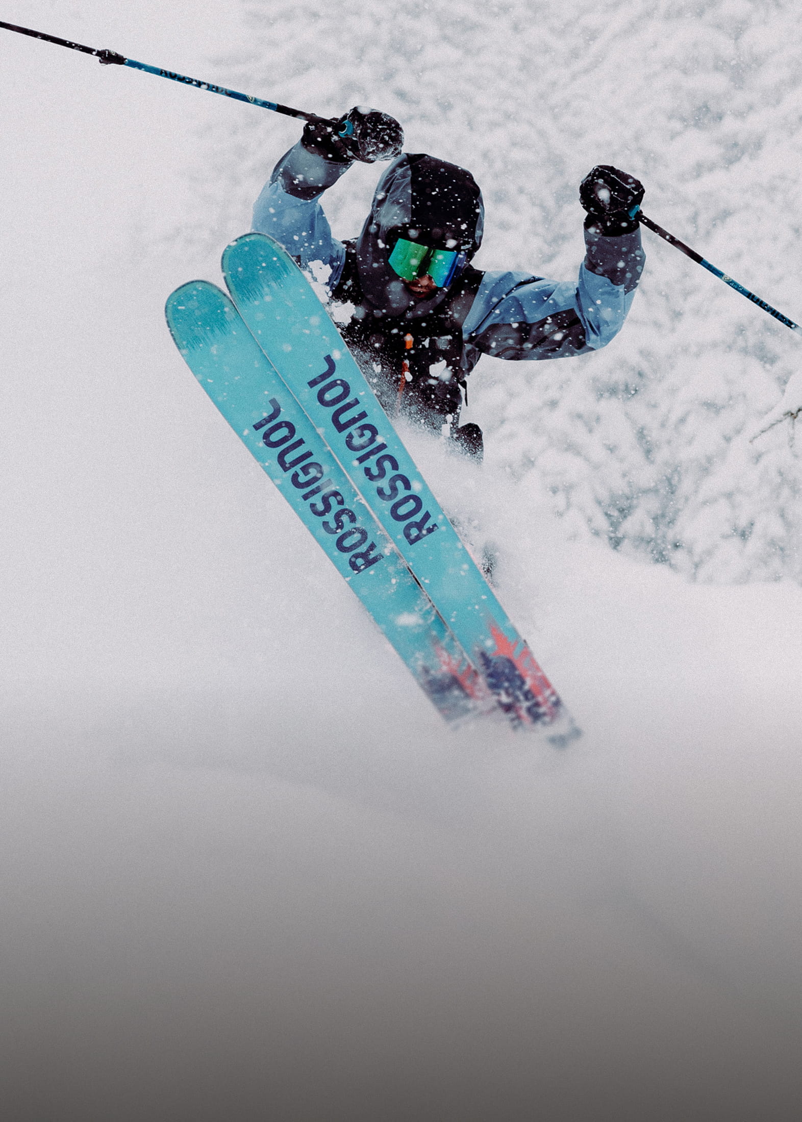 A freeride skier in deep powder, performing a jump with the tips of his Rossignol Sender skis visible.