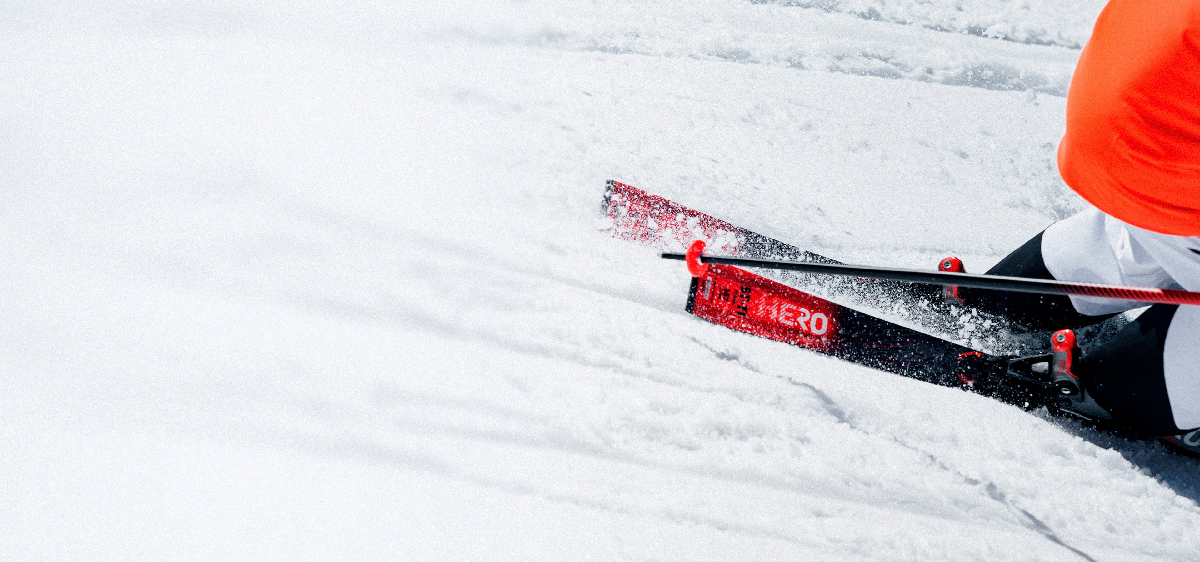 Skifahrer in einer Kurve auf präparierter Piste mit Rossignol Hero ST TI Skiern, die Schnee aufwirbeln.