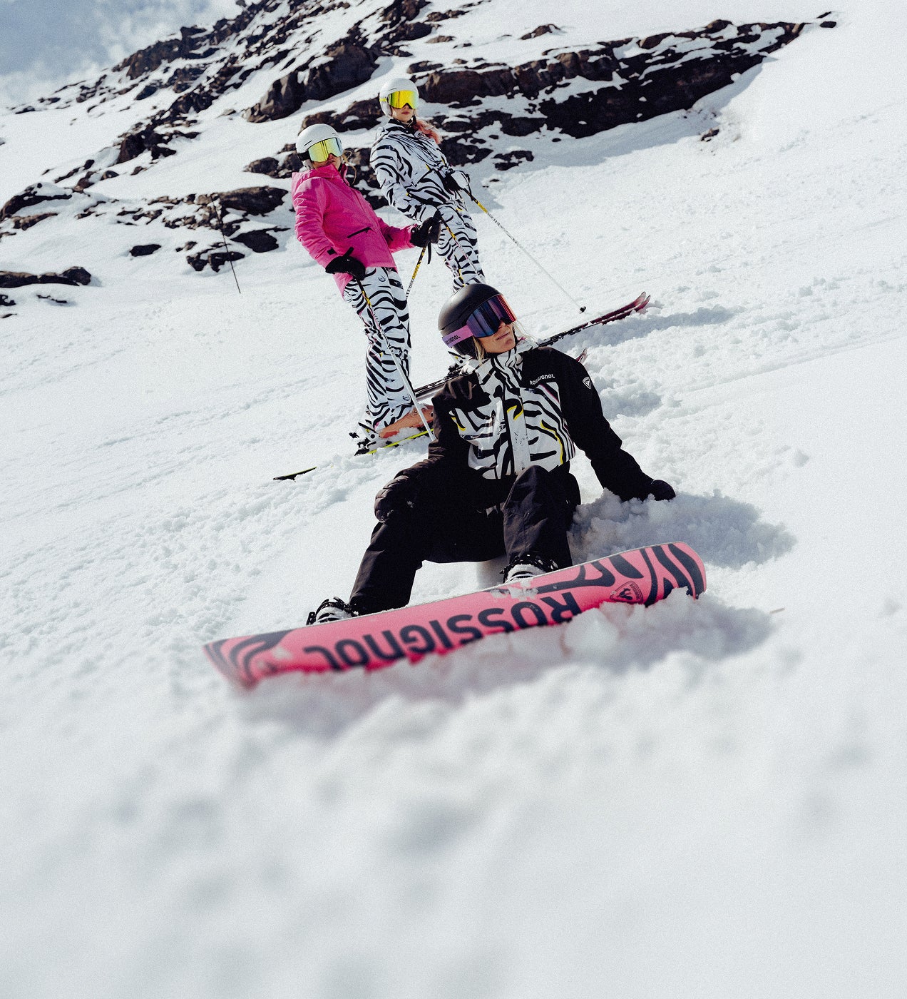 Zwei Snowboarder mit Ausrüstung aus der Rossignol Savage Kollektion auf einem verschneiten Berghang.