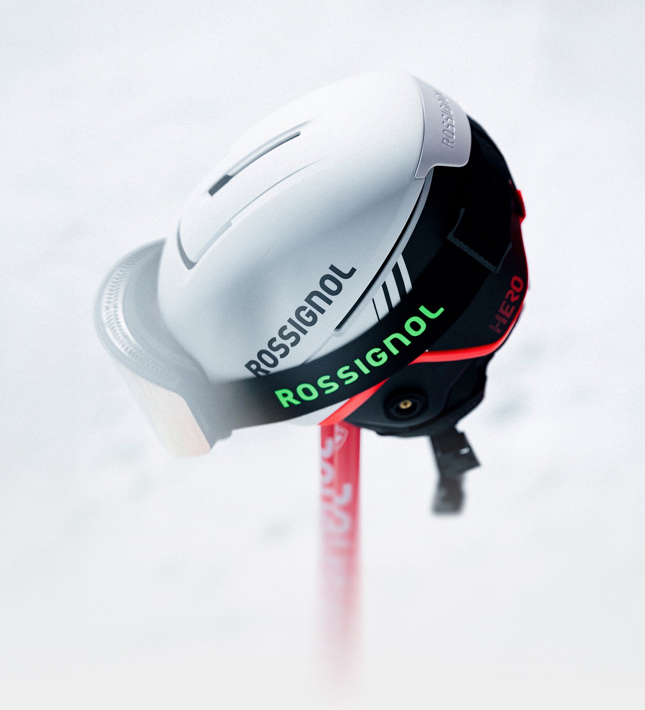 Weißer Rossignol Skihelm mit integriertem Visier vor verschneitem Hintergrund.